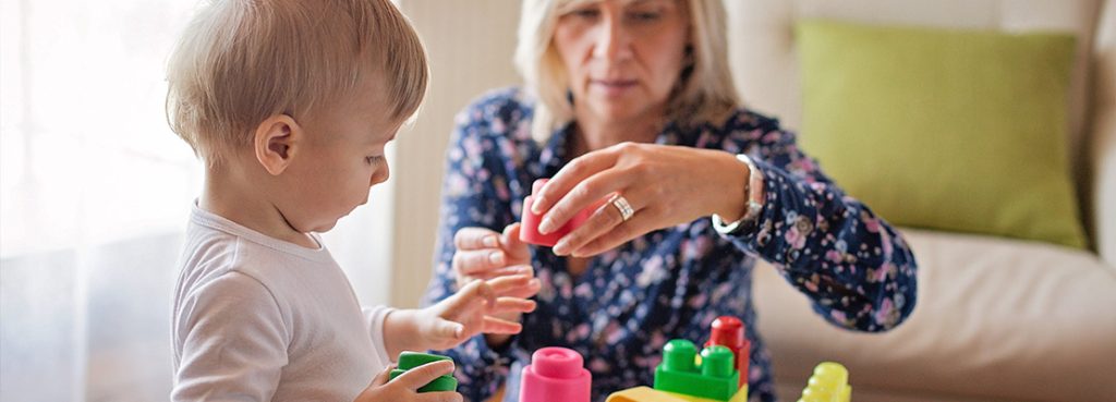 Female caregiver building legos with young child