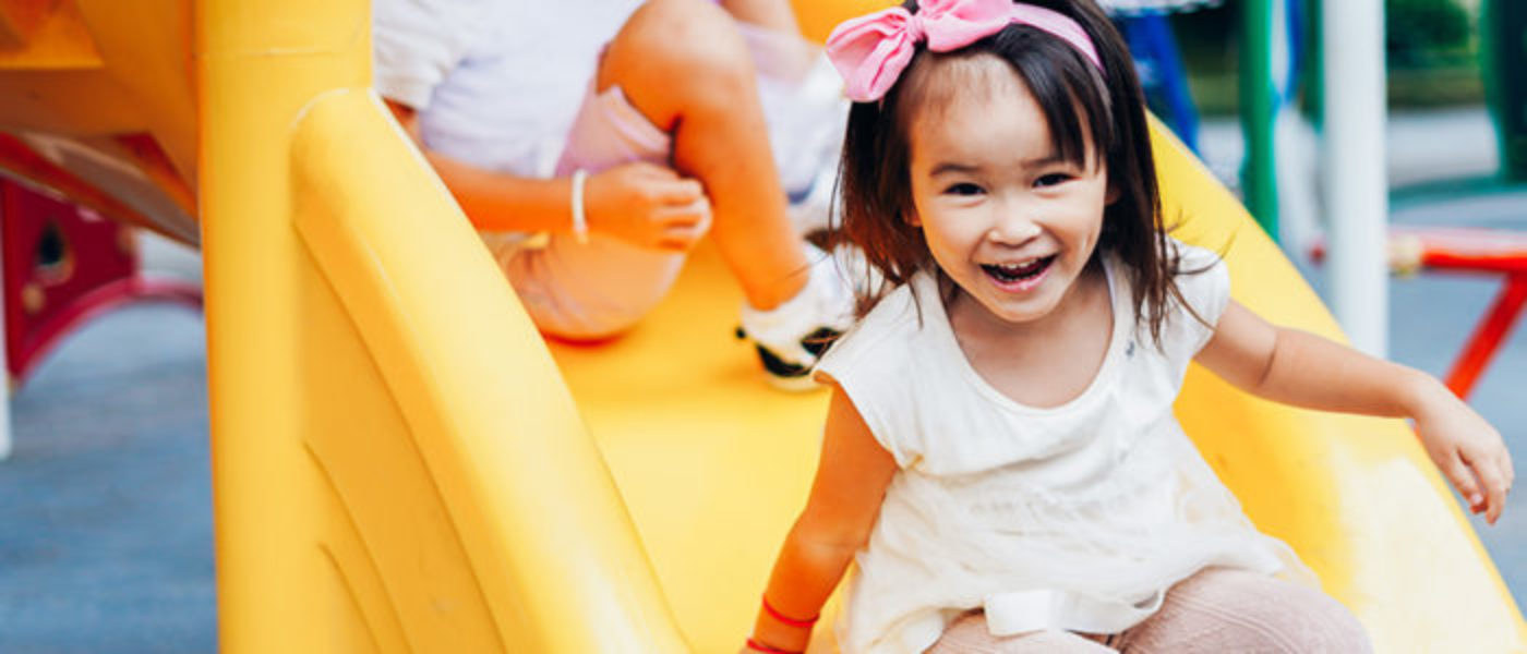 Smiling child goes down a yellow slide